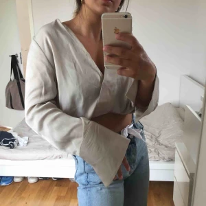  - Silvrig Omlott top från NA-KD. Vida armar och silvrigt material. Bra skick - använd en gång