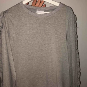  - Grå långärmad tröja från crunt med volanger på sidorna i bra skick. Aldrig använd Storlek JR Large Köptes för 300 men säljer för 70  Går att skickas mot frakt kostnad.