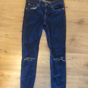 Slitna mörkblåa jeans - Supersnygg mörkblåa jeans med slitningar, dessa kommer från Gina Tricot i storlek 38. Väl använd men är fortfarande i fint skick. Köparen står för frakten.