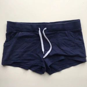  - Sköna, mjuka shorts i bomull från Divided by H&M. Praktiska fickor, vilket mjuka shorts sällan har. Sparsamt använda.   Plasten på ena snöret har lossnat lite, se bild 3. Säljes pga att de är för stora för mig.   Kan mötas upp i innerstan, Täby eller Vaxholm, annars står köparen för frakt. 