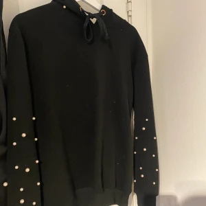 Hoddie med pärlor - Använd, men fint skick! Svart hoddie med vita pärlor. Frakt tillkommer :)