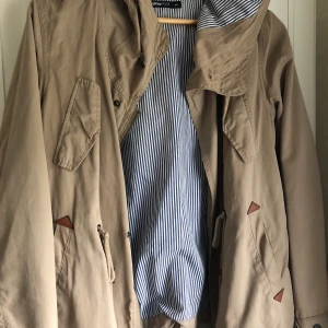 Beige jacka från Gina - Beige höstjacka med detaljer i form av fickor, knappar och mockaimitation. Storlek 34, vilket motsvarar XS/S. Använd endast ett fåtal gånger.
