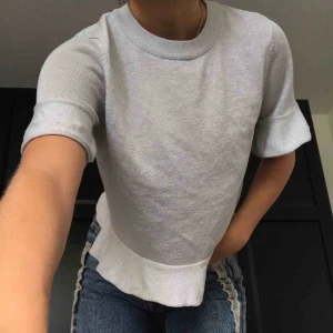  - En ljusgrå glittrig t-shirt med volangdetalj vid ärmarna och nedre kanten✨ så snygg passform