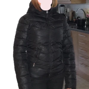 Vinterjacka - Svart, kort tight modell. Finns även fuskpäls att sätta på luvkanten. Fint skick. 