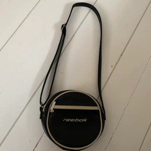 Reebok väska, vintage/retro väska. Mkt bra skick!! - En vintage reebok väska, man kan justera axelbandet. Sportig och trendig, väldigt bekväm och rymlig väska! 🙌🏻✨ Frakt ingår ej i priset (+44kr). Budgivning i kommentarsfältet! 🤗💕💕