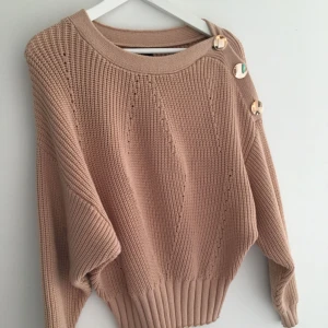  - Stickad tröja från Lindex med guldknappar på ena axeln. Inköpt i somras, endast använd 1 gång. Stl S men passar XS-M beroende på önskad passform. Frakt tillkommer.