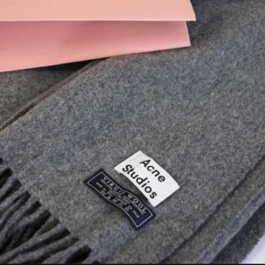  - Helt ny grå Acne studios halsduk i virgin wool. Kommer med sin rosa påse. Frakt på 89kr tillkommer. Kan mötas upp i centrala Uppsala. Stor modell. 