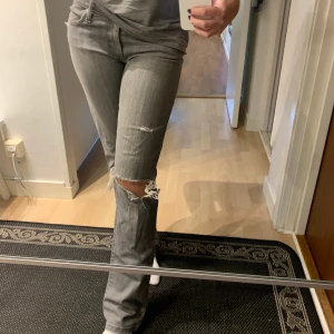 Gråa slitna lågmidjade jeans - Säljer domhär jättefina jeansen från ett märke som heter nobody, har gjort hålet själv. Dom är lågmidjade och ganska långa, jag är 170 och de är lagom långa på mig. Jag brukar ha storlek 36/38 i jeans, passar både mindre ock större beroende på hur man vill att dom ska sitta.