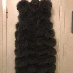 Päls väst  - Lång pälsväst storlek s, passar även m och xs. Mörkgrå färg använd va 4 gånger. Nypris 3999. Äkta päls