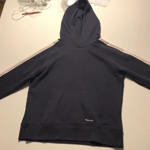 Gant hoodie strl 170 marinblå  - En oanvänd Gant hoodie från julas. Fin färg och skön. Nypris: 629kr. Säljer för 250, med tanke på att den är oanvänd. Passar både dig som tjej och kille!