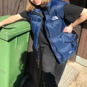 North Face väst  - En blå north Face väst köpt second hand. Den har en pytte liten fläck på baksidan av ryggen men den syns inte vid användning. Står ingen storlek men skulle säga att den sitter som en S/M beroende hur man vill att den ska sitta. Kan mötas upp i Stockholm💞Buda på