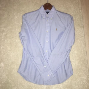  - Säljer en ljusblå Oxford skjorta från Ralph lauren. Skjortan är endast använd ett fåtal gånger. Modellen är super slim fit och är i storlek 4 som både en XS och en S kan ha! 