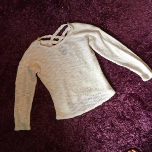  - En vit stickad tröja från Nelly med snörning på ryggen 