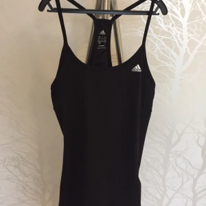  - Adidas träningslinne med inbyggd sporttopp. Material är polyester och elastan. 