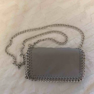  - Ljusgrå Pricilla väska från Tiamo i storlek s. Har några slitningar i metallen på sidorna (se bilder), men inget som syns när väskan är på! Nypris: 450. 🌹 Frakt tillkommer! 