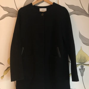 Jacka från Elvine - Svart kappa från Elvine Storlek: XS, men passar en S. Material:  80% Ull 20% Polyester Inköpt från MQ i Göteborg. Skick: Jättebra. Mitt pris: 500kr inklusive fraktkostnad. Köpt för 2500kr.