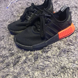 NMD_R1 - Sneakers - core black/solar red - Säljer nu mina 6 månader gammla nmds som inte är i nyskick direkt men ändå riktigt fina, det är ett litet hål fram på högra skon och dom är lite slitna inuti men de är inget som man märker av eller tänker på. Dom kostar ca 1500 nypris så jag tänker att 500 är ett rimligt pris eftersom att dom är rätt så gammla och hålet där fram sänker priset en hel del. Storleken är 37 1/3 men dom är ganska små i storleken så när jag använde dom så hade jag ett par andra skor som var storlek 38 och båda passade perfekt då.