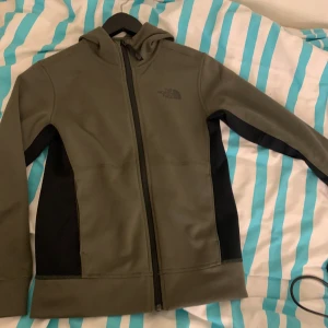 Grön kofta från The North Face - Kofta i killstrolek M (barn), men sitter som en xs dam. Koftan är i färgen olivgrön. Knappt använd 