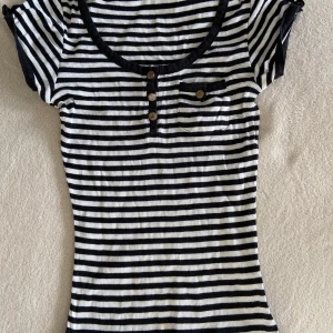 Ginatricot topp/t-shirt, storlek M - Randig kortärmad med guldiga detaljerade knappar.