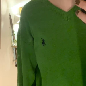 Grön stickad tröja - Grön v-ringad stickad ”grandpa sweater”. I andvänt men bra skick från polo by Ralph Lauren. Köparen står för frakt. Står ingen storlek men skulle säga att det är en M eller L
