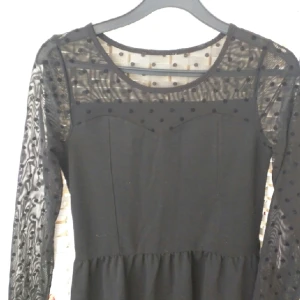  - Klänning med genomskinliga armar med prickar av sammet
Använd en gång
Slutar lite längre än till mitten av låren