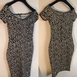  - Figursydd, skön och stretchig klänning från TFNC i London. Använd en gång! Inköpt 2016, London för 1299kr. Vackert svart/vitt/grått rosmönster från vinterns supertrend, blommigt. 