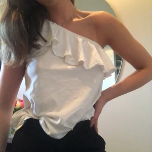 One shoulder topp! - Super söt one shoulder topp med volang. Köpt på hm, använd men i fint skick. Är fler intresserade blir det budgivning. Frakt tillkommer.