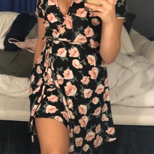 Klänning - En blommig omlott klänning med en snörring på sidan från bikbok