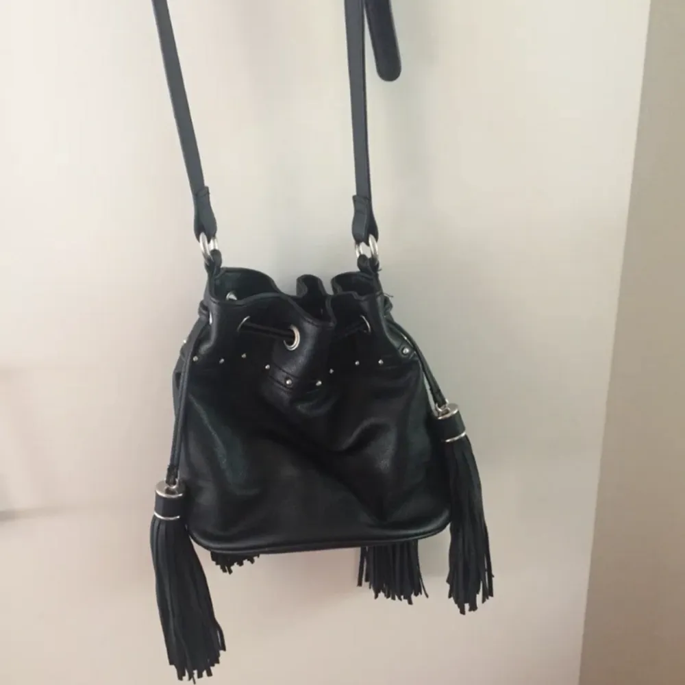 Superfin svart väska i läderimmitation! Lagom rymlig med snygga tasseldetaljer på utsidan. Frakt: 58kr. Väskor.