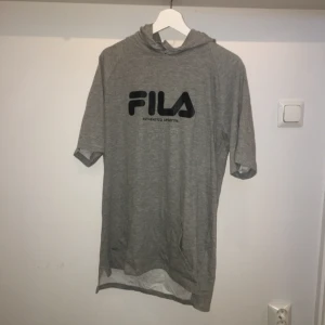  - Fila - Längre oversized T-shirt med huva. Använd ett fåtal gånger. Har en liten missfärgning vid huvan (se tredje bilden), men det är inget som syns när man har den på sig. Köparen står för frakt