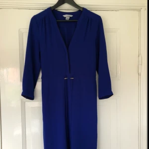  - Storlek 36 i gudomlig blå färg. Fint skick förutom märken på knapparna. Klänningen slutar precis ovanför knäet. Klänning är i polyester och elastan.