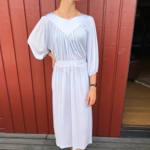  - Klänning 50-tal i tunt ljusgrått nylontyg.  Alla klänningar är i mycket fint skick! Denna säljs billigare pga av har små fläckar,ej mycket synbara.  Modell är 172cm och S. Möts upp i centrala Göteborg annars tillkommer frakt. 
