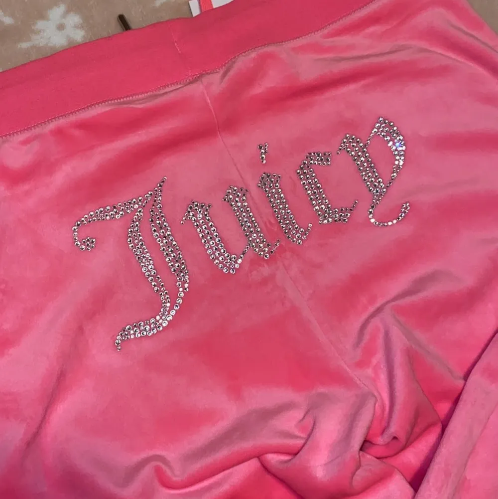 Säljer nu dessa två par Juicy Couture mjukis byxorna. Byxorna är aldrig använda & båda har prislappen kvar, anledningen till varför jag säljer de är för att jag inte haft tiden till att lämna tillbaka dom. Datumet för returen hade gått ut. Byxorna är inte i min storlek och därmed kan någon annan få en användning utav de.  Båda byxorna är i storlek (L)  Byxorna är i två olika modeller som ni kan se på bilderna. De ljusrosa har resårband i ändarna av byxorna samt fickor men även resårband i midjan.  De mörk rosa byxorna är en mer ”vanlig” modell och är utsvängda byxor med vanlig knytning i midjan. Båda byxorna har Juicy couture märket i diamanter på bakdelen.  Byxorna är köpta för 1000kr styck & säljs för 700 ( priset kan diskuteras vid snabb affär). Jeans & Byxor.