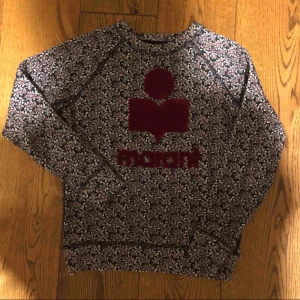 - Tröja från Isabel Marant Étoile i college modell med tryck i sammet framtill. Tröjan har ett mönster av små blommor i vinrött och vitt sammetstrycket är rött i färgen. Tröjan är använd två gånger och så gott som ny, plagget köptes in för 2300kr.