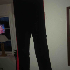  - Pösiga byxor med röd rand på utsidan av benen från Gina Tricot I mycket bra skick