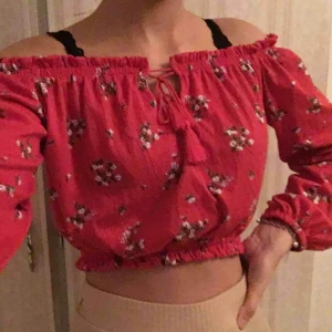 - Aldrig använd. Röd crop top off shoulder med blommor på. Pris kan diskuteras