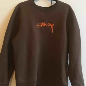  - Supersnygg sweatshirt från Stussy i chokladbrun färg med orange tryck på framsidan med loggan på. Använd max 3 gånger och därav i jättebra skick!!!! Köpt på killavdelningen men funkar även som tjej 