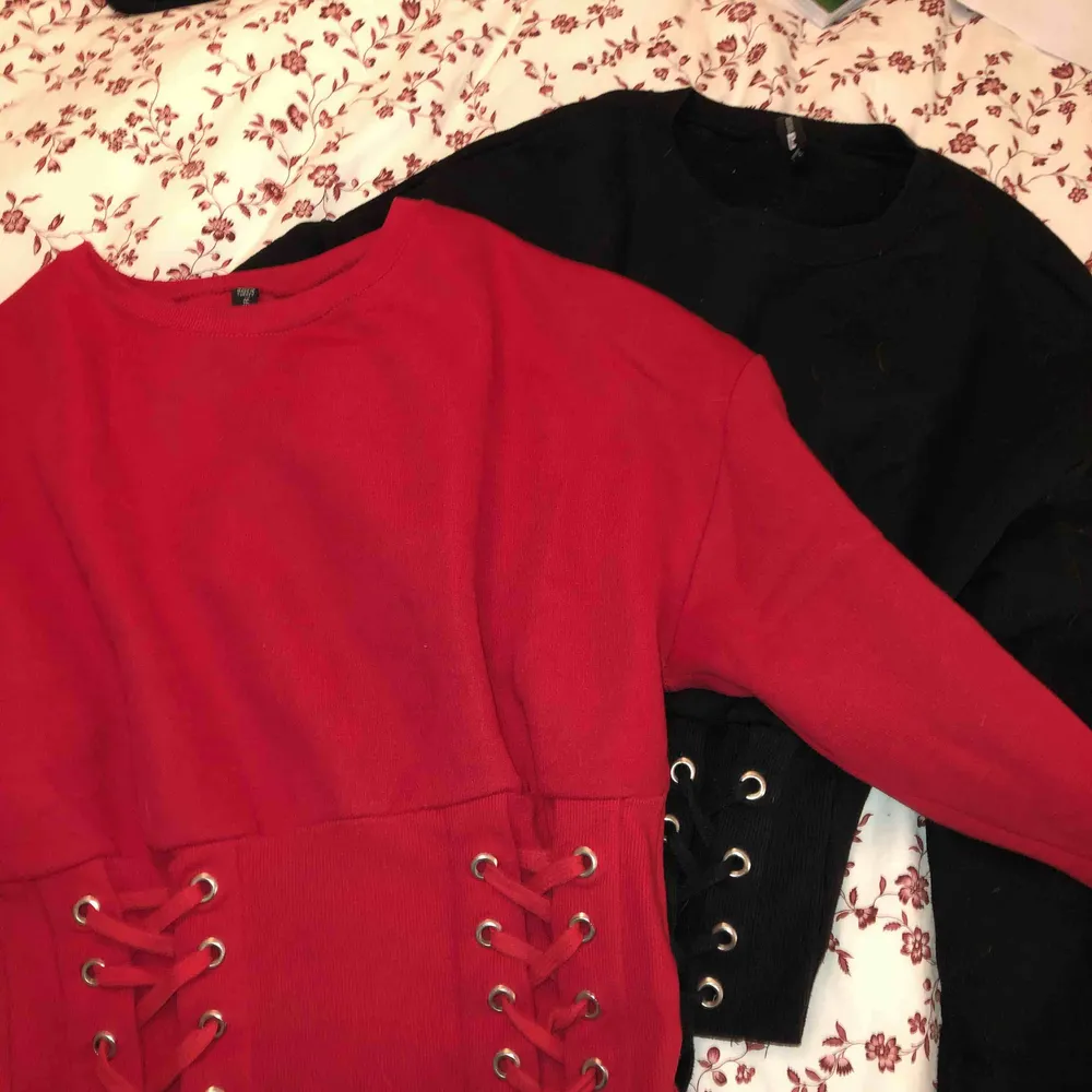 Två stycken tröjor med korsetbandning på den nedre delen.  40kr per tröja men 60kr för båda. Den röda är i storlek M och den svarta är i storlek S men de passar XS till M. Tröjor & Koftor.