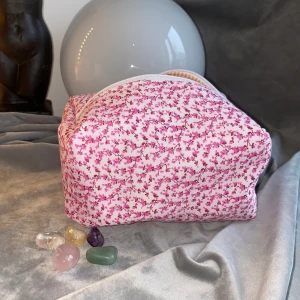 Småblommig rosa necessär - Necessär med rosa små blommor som yttertyg, ett vitt mellantyg (syns inte) och orange randigt innertyg. Ca 19 cm lång, 11 cm bred och 10 cm hög. Jag hobbysyr bara så kan inte lova raka sömmar eller 100% felfritt. Skickas med frimärke: 22kr och filmar när den skickas. Är din för 100kr plus porto