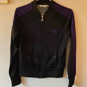 Adidas Three stripe  - Najs tröja från Adidas. Svart med lila ränder, stl 38 🤟🏼