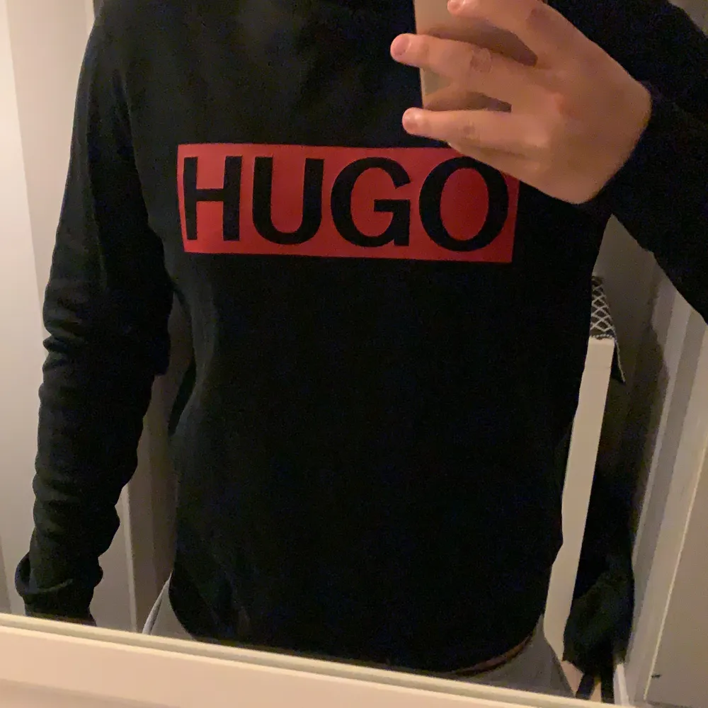Svart Hugo Boss Sweatshirt med röd logga med texten ”HUGO”. Använder ej längre och den har även blivit för liten, nypris 999:-. Tröjor & Koftor.