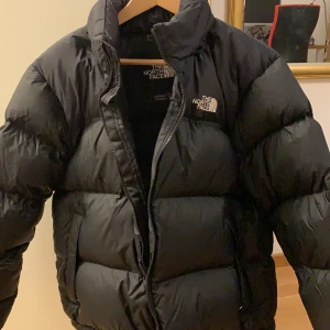 The northface nuptse jacka 1996 - Fyllig och varm dunjacka med dem klassiska nortface ”skalen”. Inbyggd luva i kragen. Trendig och stilren jacka som passar nu i kylan.