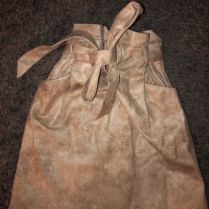 Beige kort kjol - Beige kjol som sitter bra vid midjan, orm textur på! 