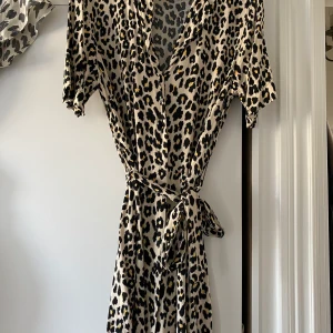 Storlek 40 - Väldigt fin somrig klänning i ledopardmönster med ett knyte i midjan. Kan användas som klänning med även som som kjol med bara en stickad tröja över.