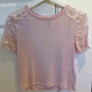  - En tunn t-shirt med spetsärmar, perfekt till sommaren! På ett fåtal ställen har små maskor dragits ut (se bild 3) men det är inget man tänker på 