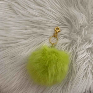  - En gröngul accessoar som man kan ha på väskor eller som nyckelring. Den har ett guldigt spänne.  Frakt kan tillkomma det beror på.  Den är aldrig använd och nypris är 99kr