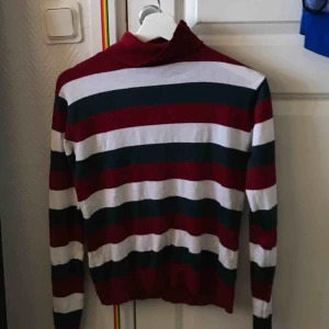  - Randig polotröja i grönt, rött och vitt! Bra skick.  Köparen står för frakt, kan mötas upp i stockholmsområdet. 