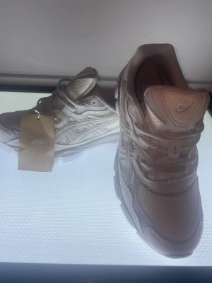 Beige Asics sneakers med mesh - Snygga beige sneakers från Asics med detaljer i mesh och syntet. Skorna har en chunky sula och klassisk snörning. Perfekt för dig som gillar sportig och modern stil.