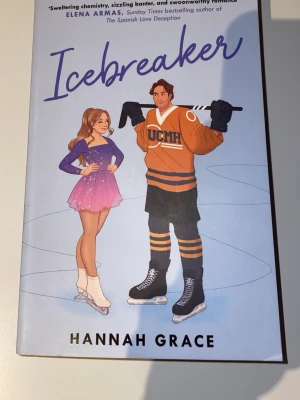 Icebreaker av Hannah Grace - En skönlitterär bok med ljusblått omslag som visar en tecknad konståkare och en hockeyspelare. Titeln 'Icebreaker' står i stora bokstäver och författaren är Hannah Grace. Perfekt för dig som gillar romantik och sport.