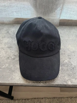 Hugo boss keps  - Oanvänd Hugo boss keps, vet ej storlek. stått i en hylla så är dammig. 